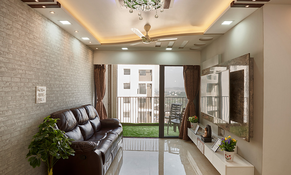 Modern eclectic style living room design in in dombivil mumbai with a TV unit, sofa, brick cladding and ceiling light looks elegant.