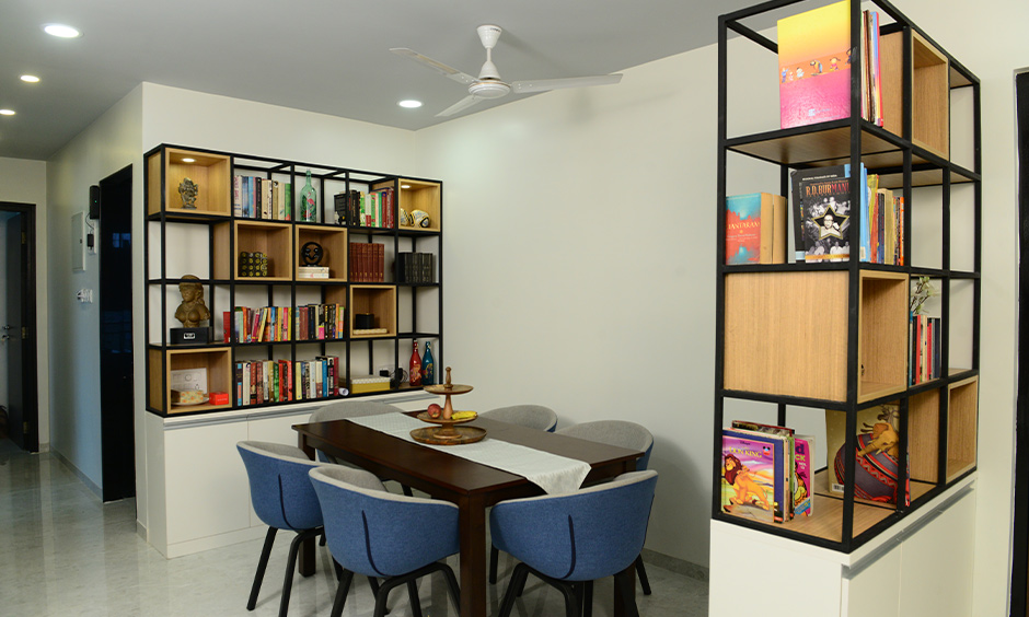 Small 2bhk dining room designed by interior designer in Mumbai with open bookshelves, dining table, and chairs