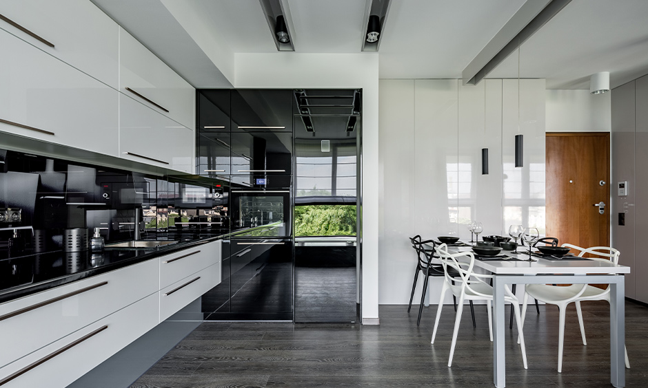 Kitchen cum dining area with high gloss laminate kitchen cabinets in minimal white and black design.