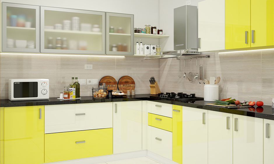 L-shaped kitchen with modern high gloss kitchen cabinets in yellow and white colour combination looks splendid.