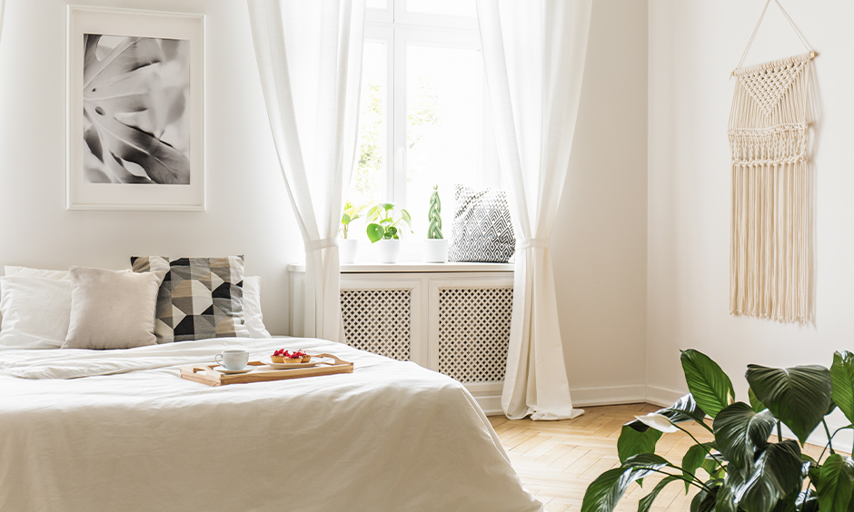 Simple white bedroom curtains in flowy texture for a small window are charming.