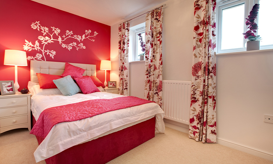 Bedroom pink color combination for wall with floral printed curtains and pink cushions adds vibrance to space.