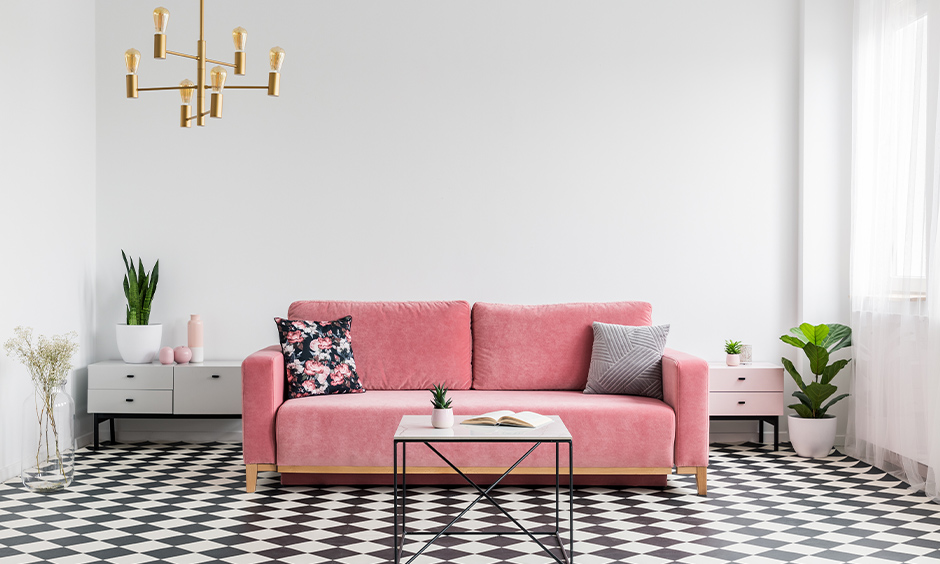 Black and white floor tiles in the room bring a bold look with a pink sofa and hanging light.