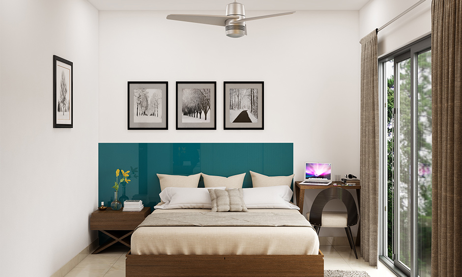 Wooden headboard design in ocean blue colour and glossy finish in the white bedroom looks bold.