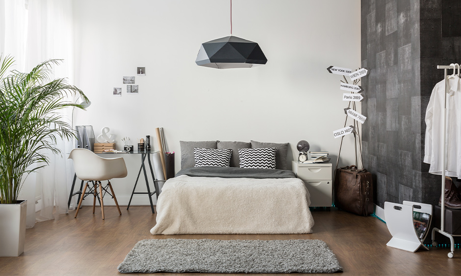 Grey and white bedroom colour combination designed with fancy hanging light, wooden flooring, and study table classic look.