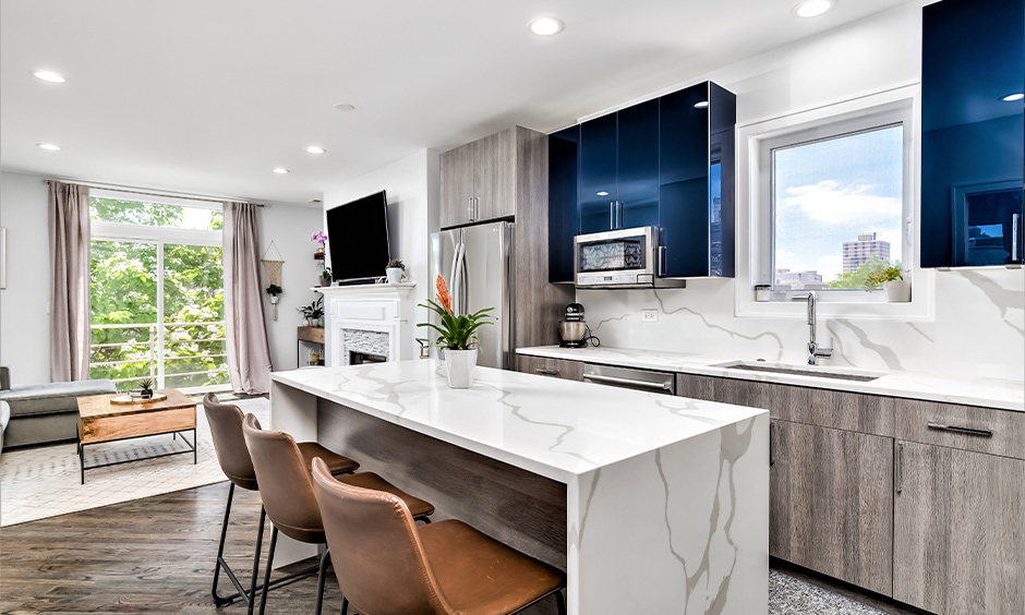 Greyish brown two tone kitchen cabinets and island with a waterfall marble kitchen island 