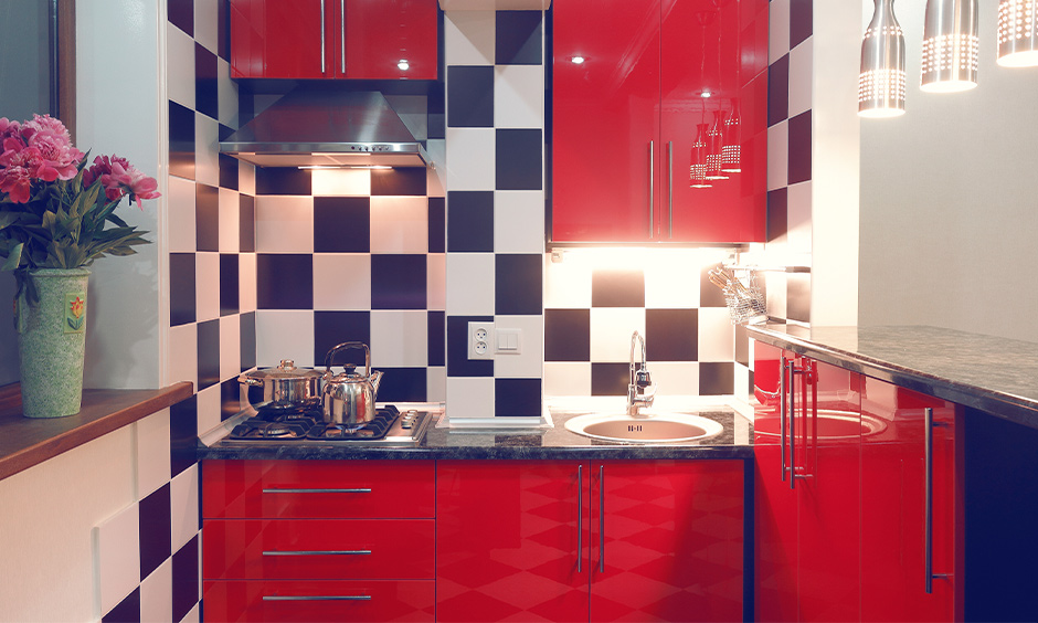 Small kitchen with hanging lights, red cabinets and backsplash look bold is the Indian style kitchen design for small space.