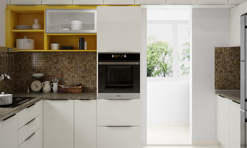 Indian style small modular kitchen design with white cabinets, yellow shelf and brown backsplash looks vibrant.