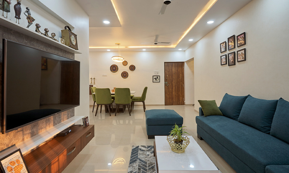 3bhk white living cum dining area design in kalyan city mumbai with tv unit, false ceiling and sofa.