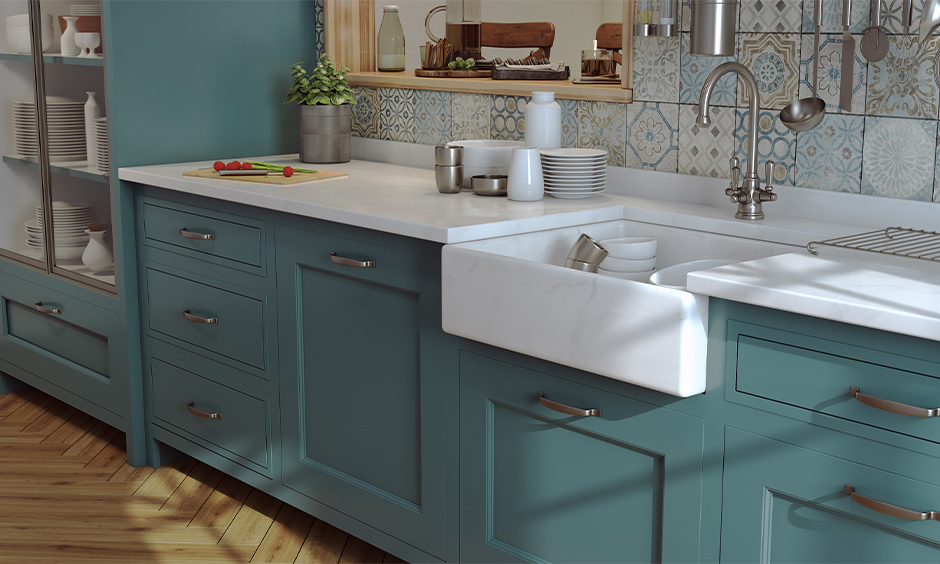 White marble farmhouse kitchen sink with cabinets below in green colour looks elegant.