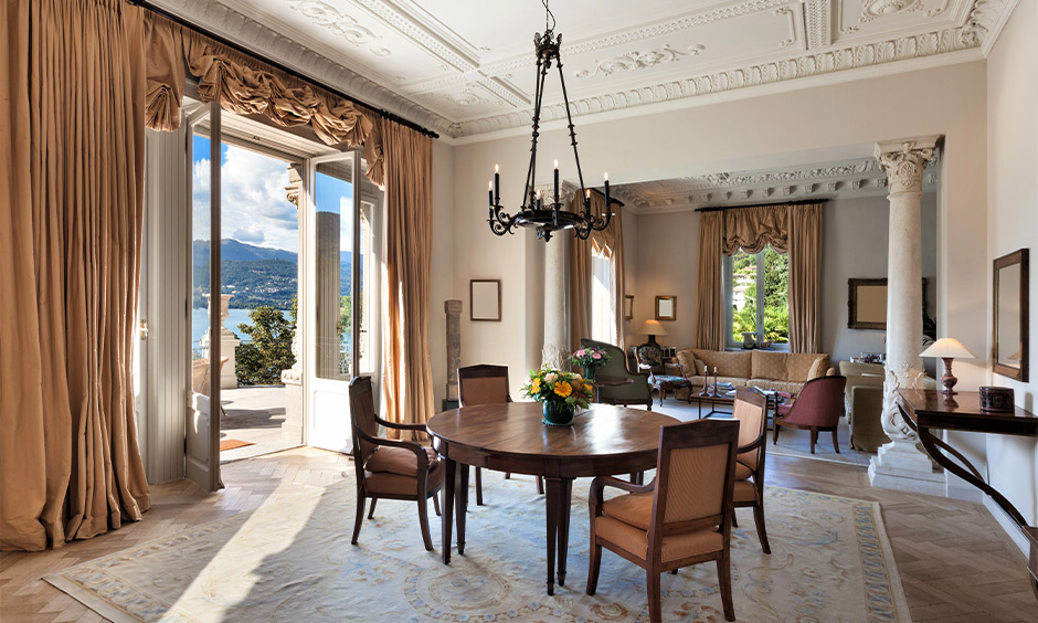 Dining area design in french interior style with candlestick chandelier, rustic-looking drapes, and round dining table