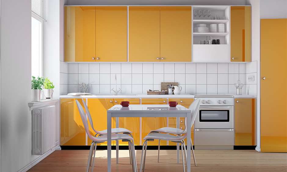 Simple small kitchen design in Indian style with orange cabinets and white dining table looks chic.