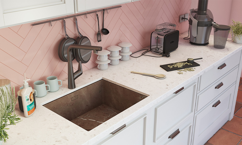 Undermount brown marble kitchen sink design with a white stone countertop looks charming against pink kitchen backsplash.