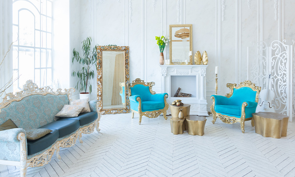 White herringbone tile floor in the white room with ocean blue colour chairs and golden table brings an elegant look.