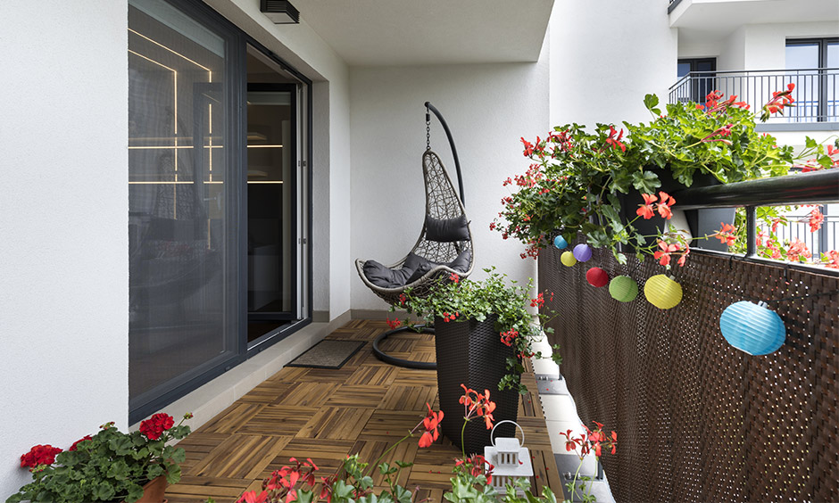 Balcony with a movable swing, potted plants and wooden flooring is the best interior hack for a busy mom.