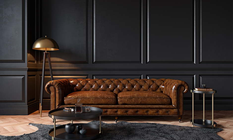 Two-seater Chesterfield leather sofa against the black wall lends a classic vintage look is the trending sofa design.