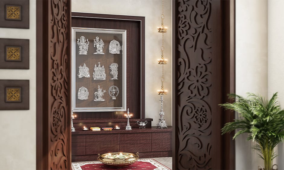 Custom traditional pooja room designs for your home with yellow lights and hanging brass diyas on either side