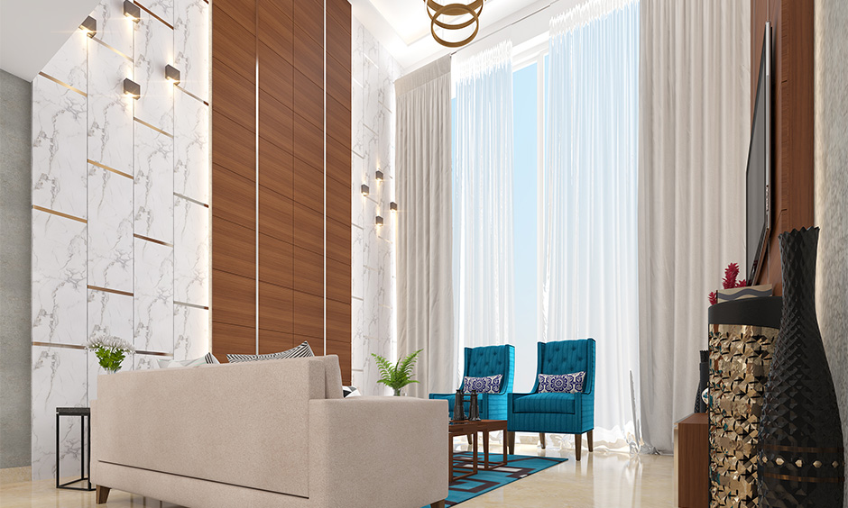 Floor to ceiling wooden wall designs in the living room with marble flooring adds grandeur to the interiors.