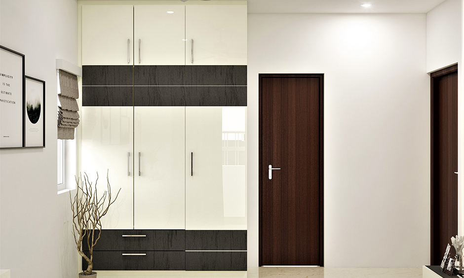 Modern 3 door wardrobe design with drawers below and laminates in dark grey and white colour combination looks luxurious.