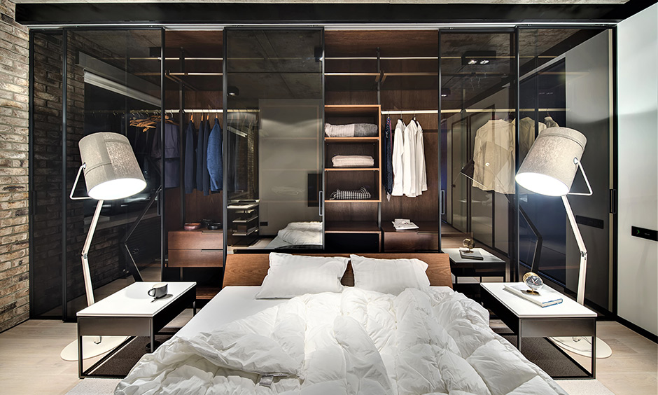 Master bedroom wall wardrobe designed with sliding partly transparent glass doors in black lends a classy look.