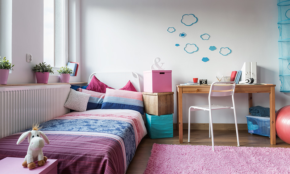 White study room decoration with a pink woollen rug, green plants, wooden table and a metal chair adds a dreamy vibe.