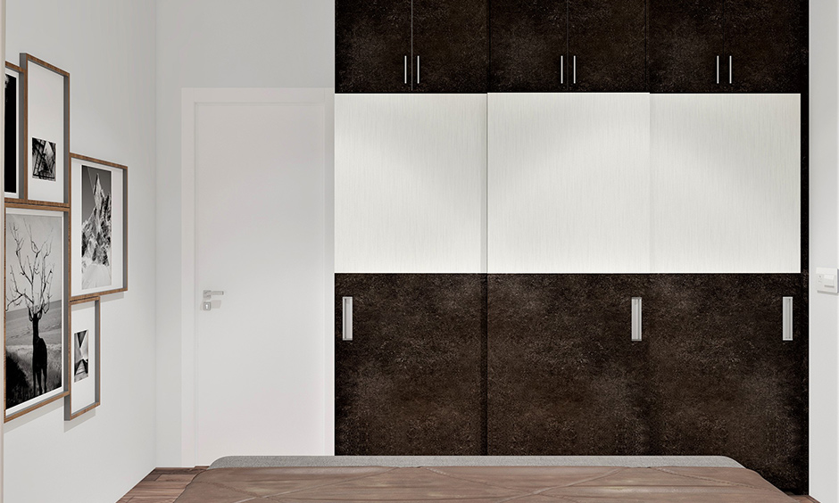 Simple 3 door wardrobe design in dark brown and white colour combination lends a cosy vibe to the bedroom.