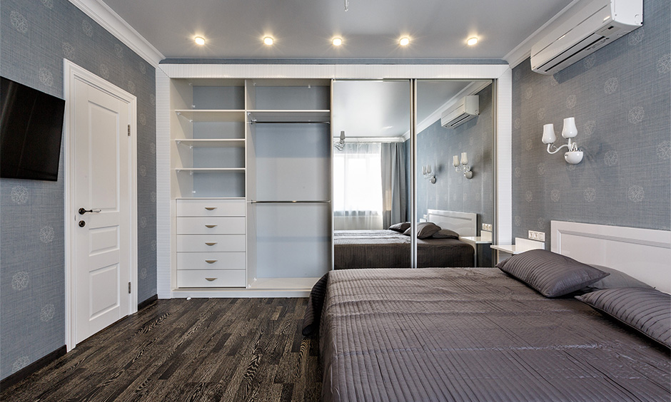 The full wall wardrobe design with mirror sliding doors in the bedroom looks sleek and minimalistic.