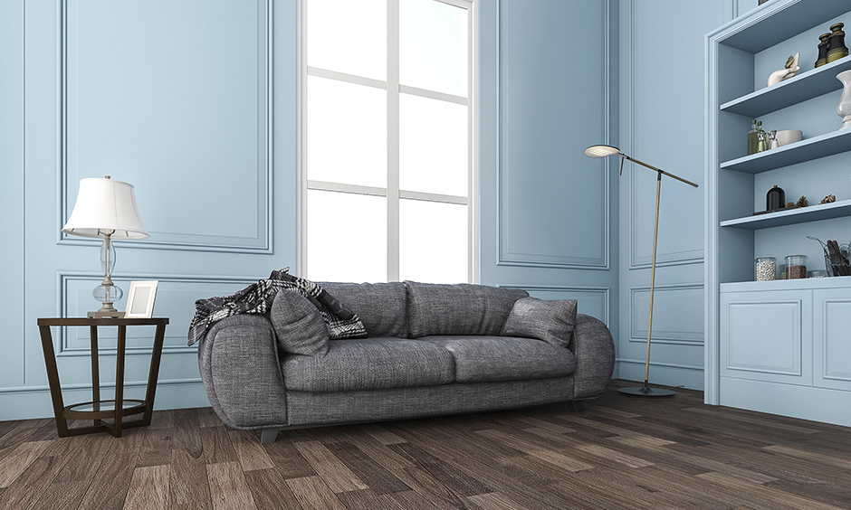 The dark brown wood laminate flooring design in the pastel blue living room looks charmed and chic.