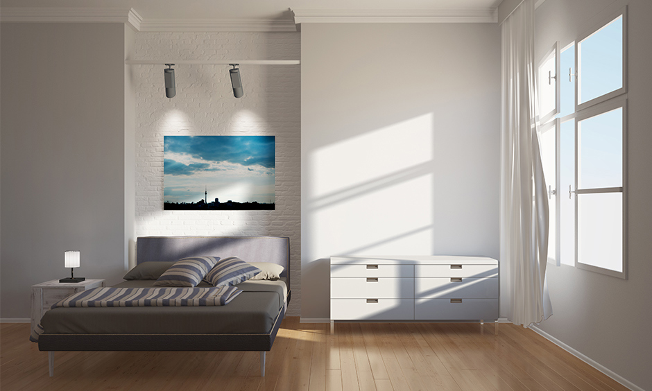 White bedroom home interior in a minimalist design lends aesthetic look with brick cladding accent wall and wooden flooring.