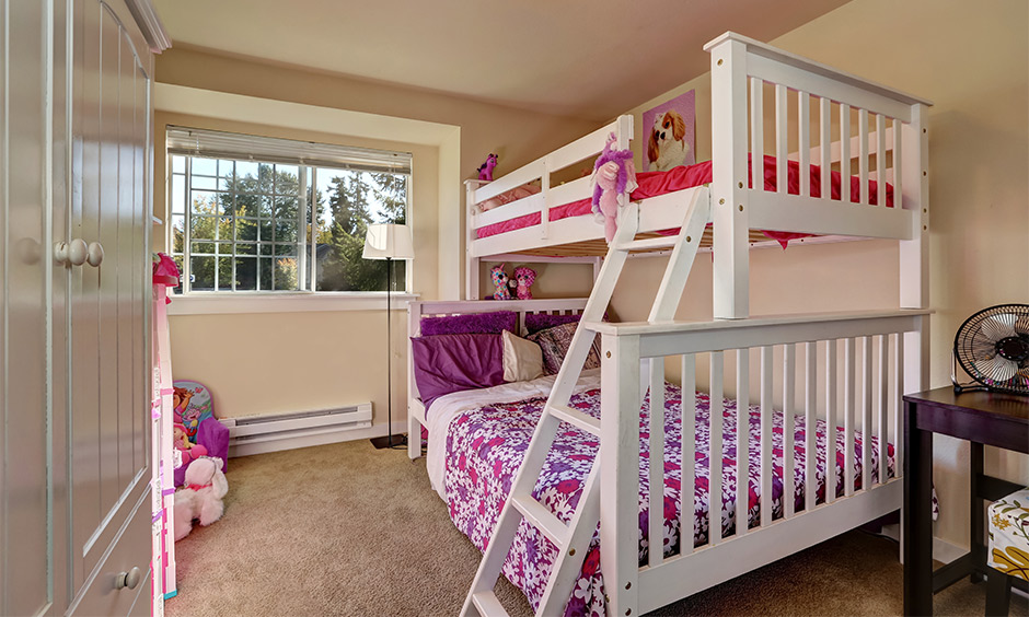 Bunk beds for girls with pops of pink with pink soft toys hung along the bed