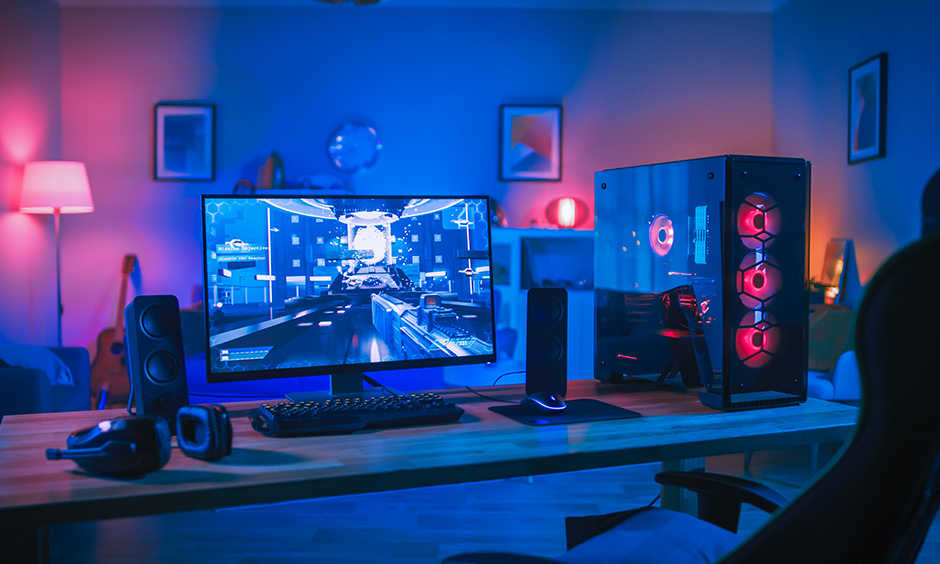 Computer gaming room design in white colour with ambient lighting and wooden table lends a sleek look.