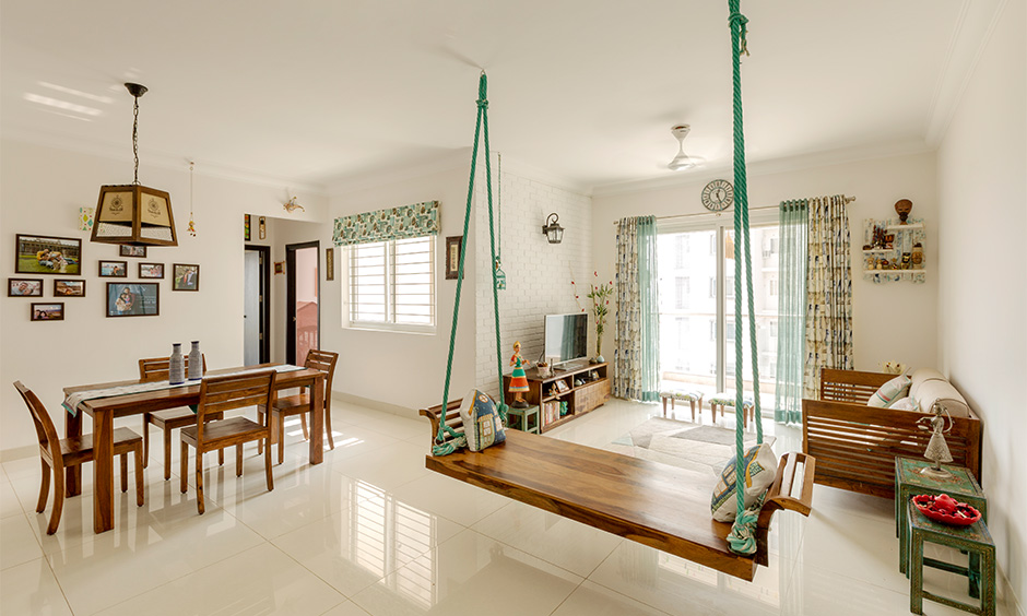 White minimalist living room cum dining area in Indian traditional style with wooden furniture brings a soothing look.