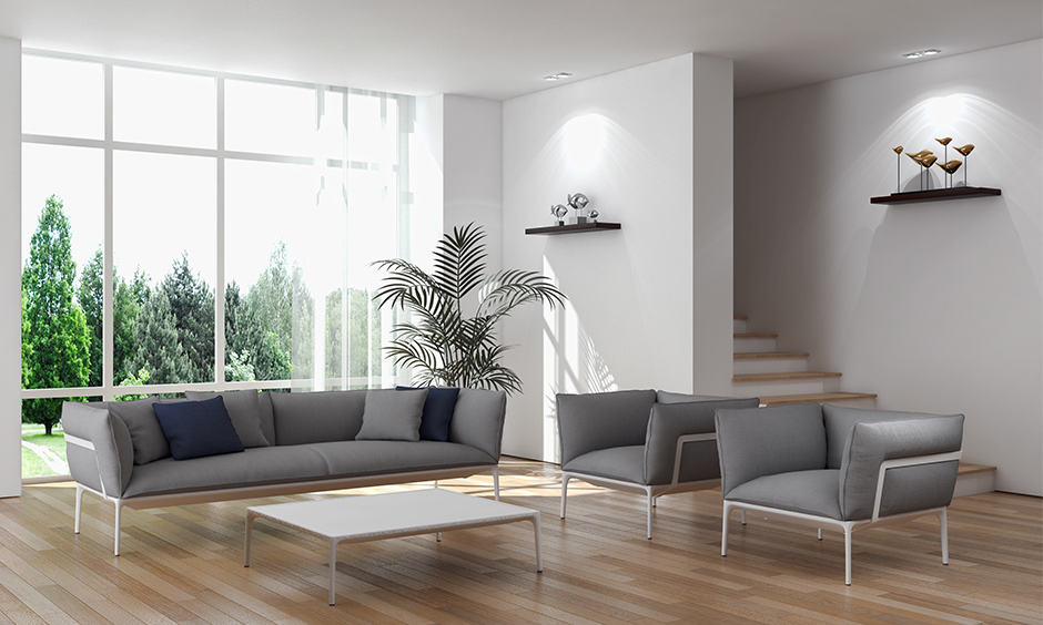 A white living room with stairs hidden behind a wall with wooden steps created a minimalistic look.