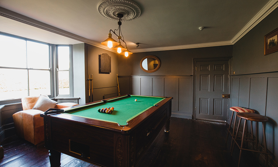 Pool table gaming room designed in grey colour with classic lights and table looks vintage.