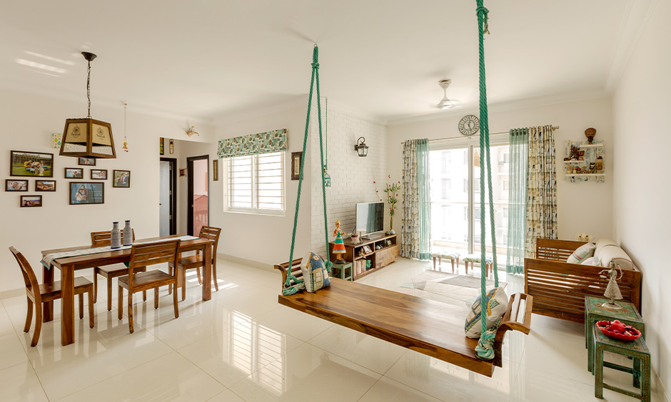 Small minimalist home design, white living cum dining area with wooden tv unit, swing and dining table exude natural vibes.