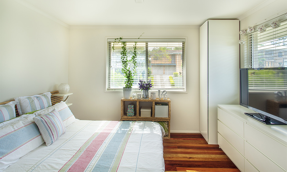 Small bedroom with corner cupboard design in white laminate and the TV unit has a chest of drawers.