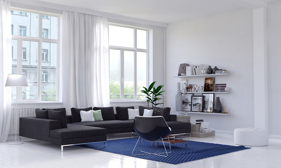 Minimalist home design India, White living room design looks sleek with a blue rug and brown sofa.