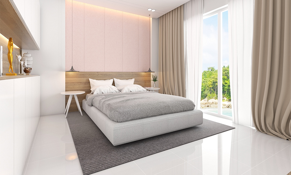 A white minimalist bedroom design with a baby pink accent wall by the headboard and headboard in wooden finish look chic.