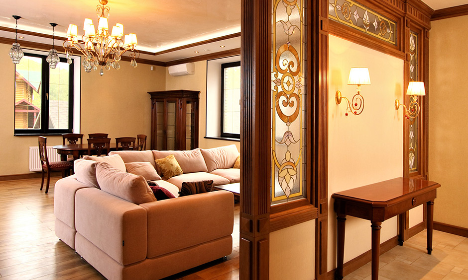 Indian villa design, villa foyer area has mirrors in golden frames, two wall lamps and a wooden table.