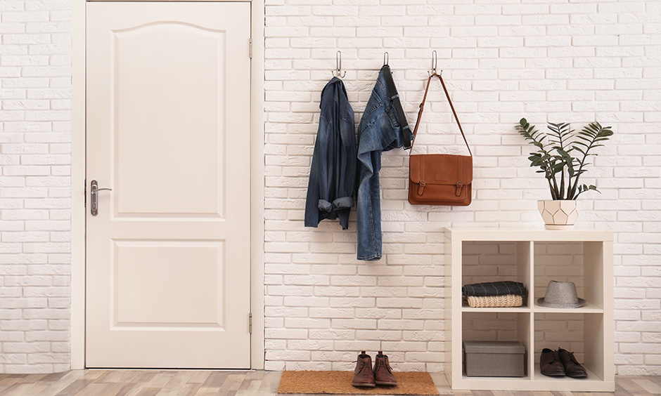 Modern foyer area design with white brick wall cladding and wooden table with open shelves lend industrial look.