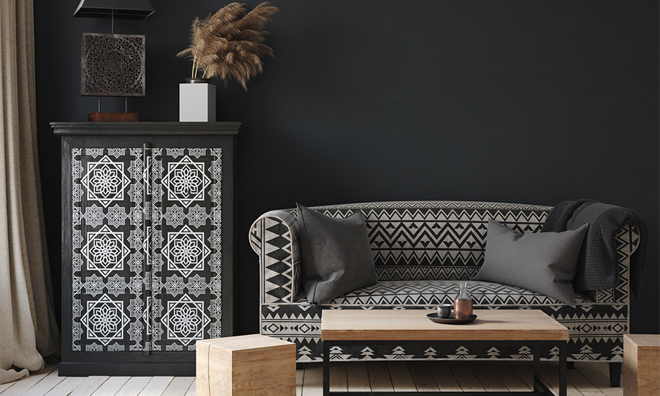 Tribal decor idea, a living room decorated in monochrome and intricate detailing wooden furniture in paint adds charm.