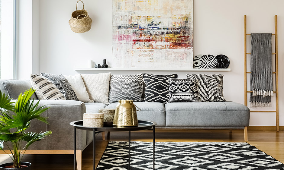 The living room has tribal decor items like abstract art, cushion, collectables, and brass serveware look splendid.