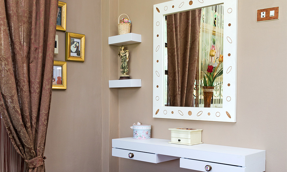 The wall-mounted corner dressing table design in white colour is perfect for small rooms and reduces floor clutter.