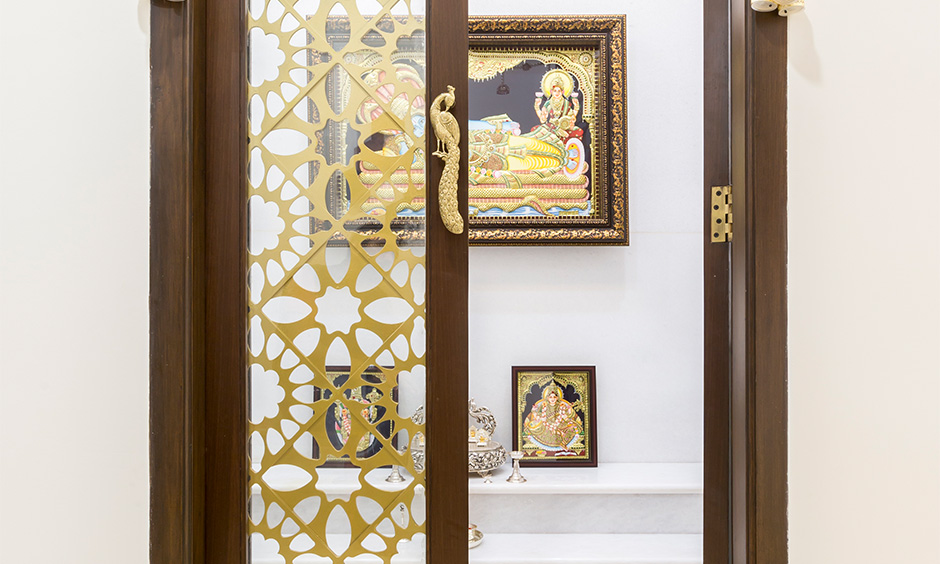 Wooden panel door design with jaali pattern and gold peacock handles for the doors lends a traditional look.