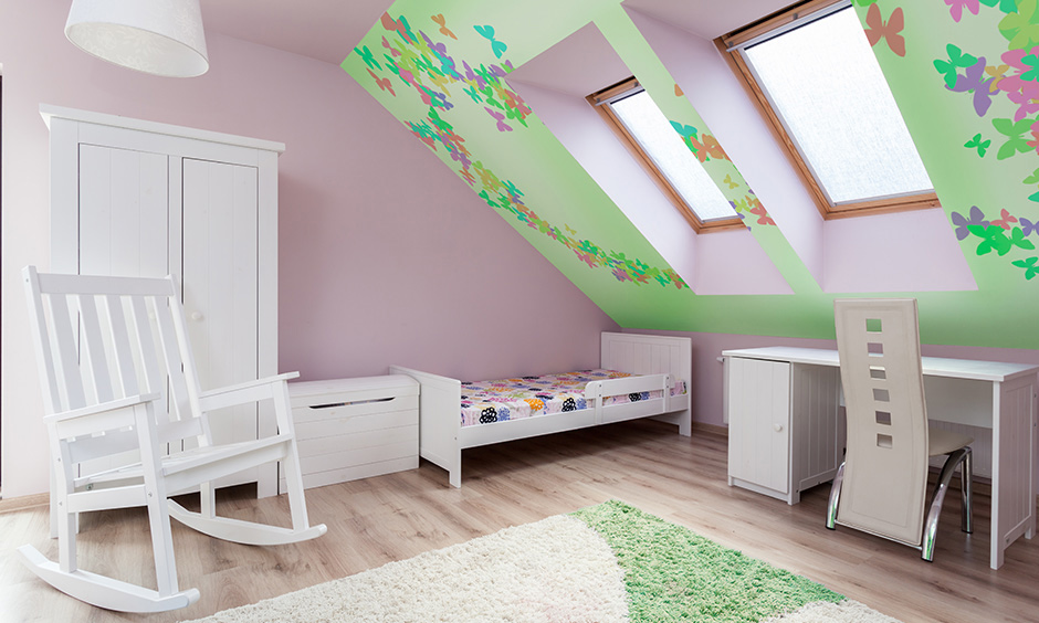 Attic bedroom idea for kids, kids room with white furniture and colourful art around the skylights adds dimension to space.