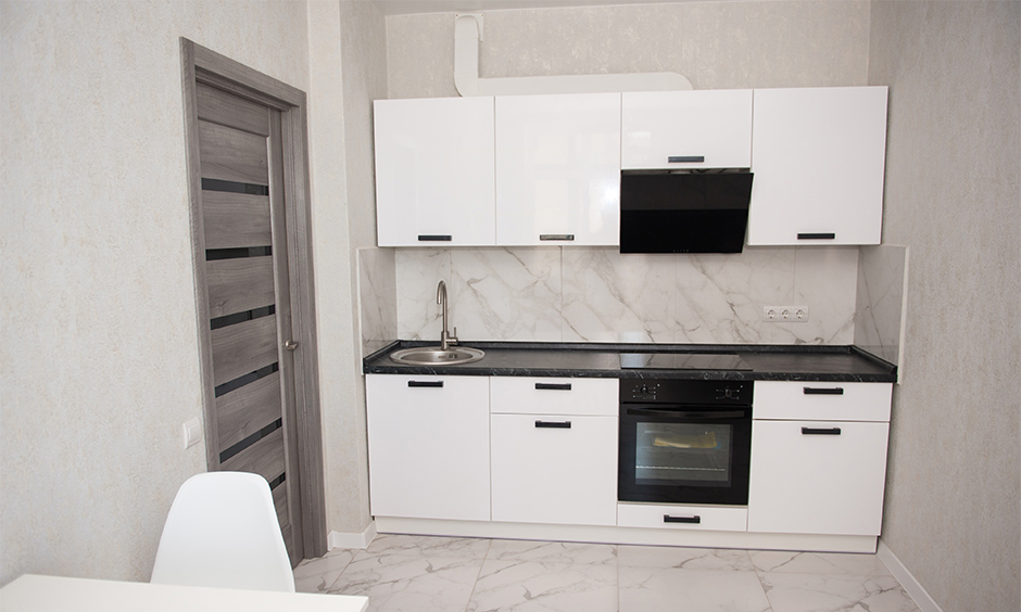 The studio apartments' ultra-small straight line kitchen design features enough storage space to hold crockery