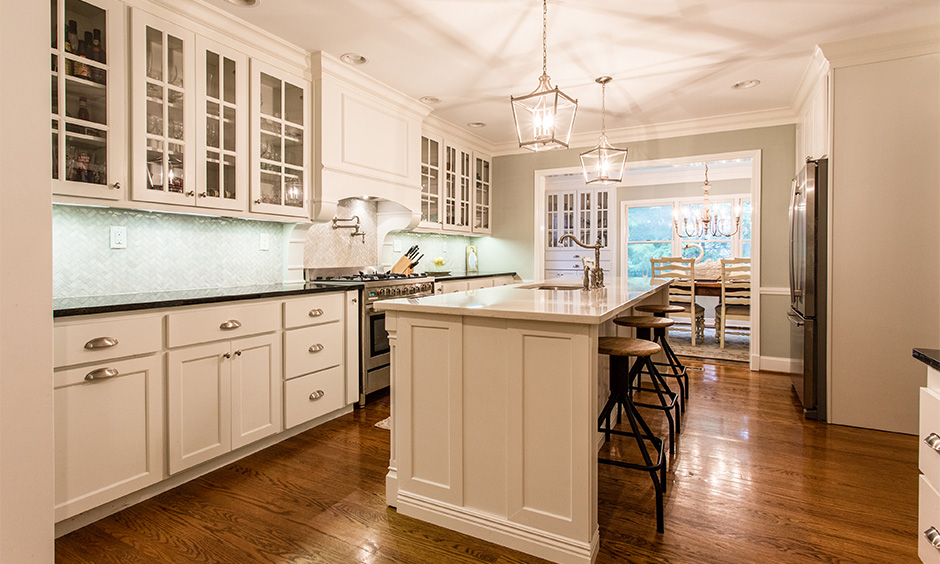 French kitchen island has chic pastel laminates, semi-rustic lights and wooden flooring