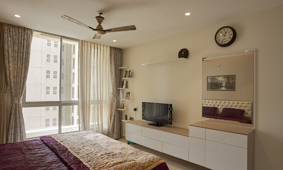 Tall floor-to-ceiling light curtains make a small master bedroom look bigger