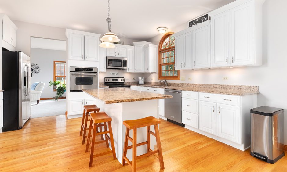 A modern kitchen with center island granite top and wooden stools gives a classy look