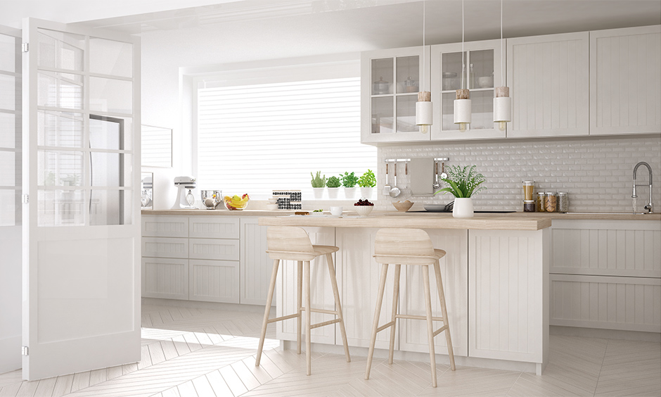 All-white Scandinavian kitchen with a light wood accent on the countertop and chairs adds natural appeal